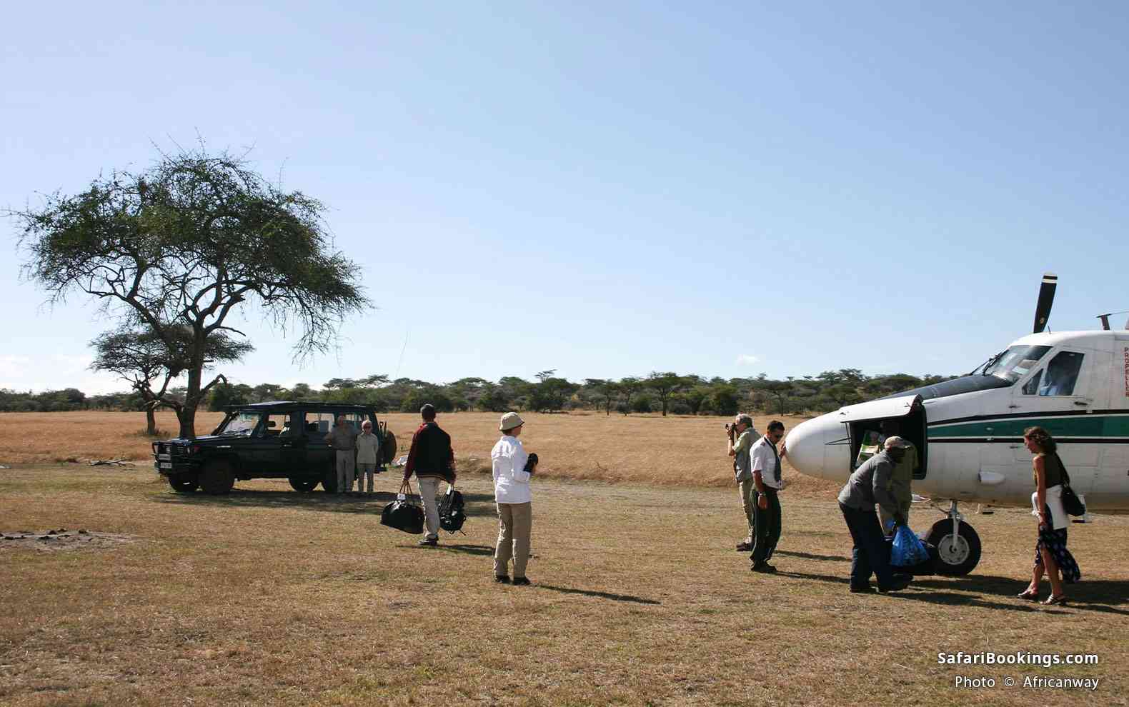 Travelers disembarking a small aircraft in Masai Mara National Reserve