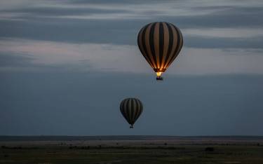 Balloons floating above the savannah plains before sunrise
