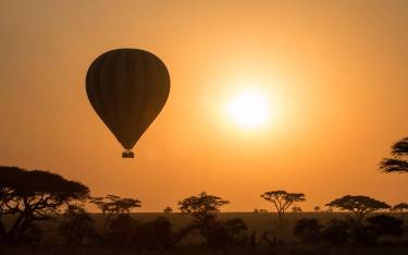 Hot-air balloon at sunrise over the Serengeti